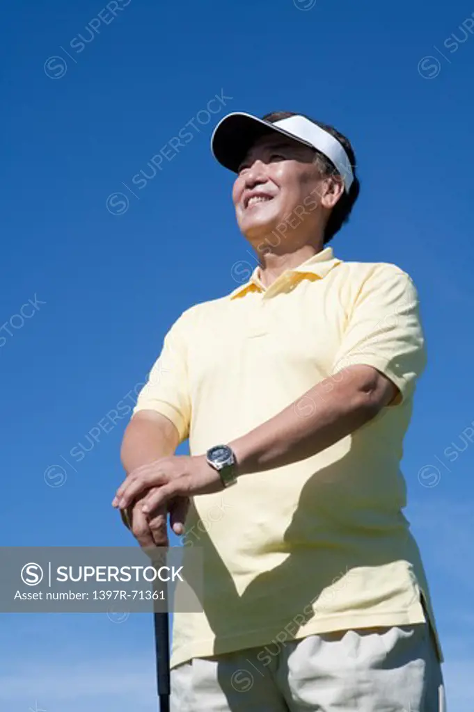 Senior man holding golf swing and looking away with smile