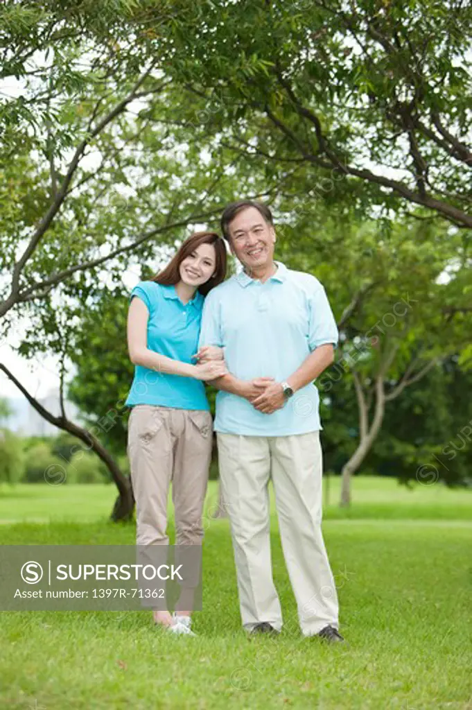 Father and daughter standing on lawn with smile