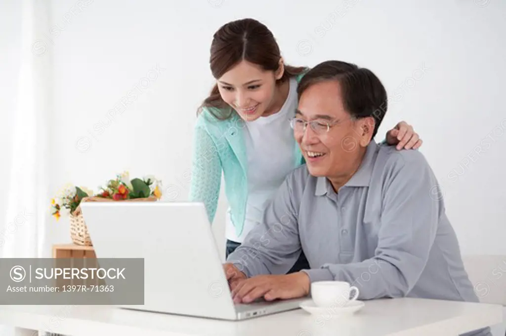 Father using laptop and smiling happily with his daughter