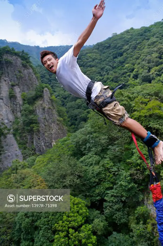 Man bungee jumping with arms outstretched