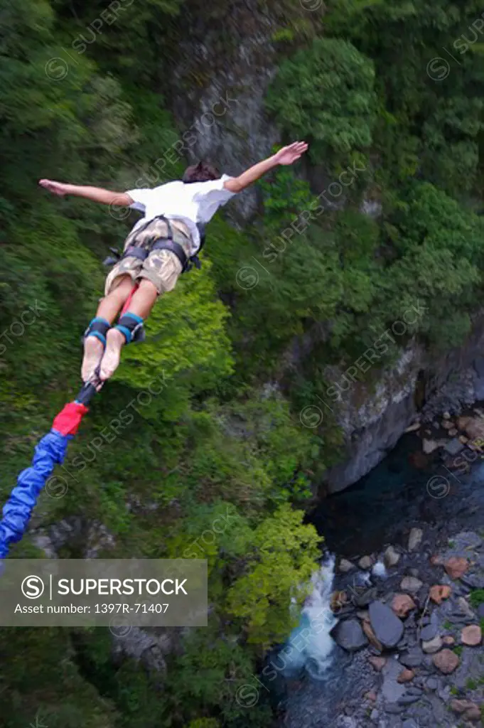 Rear view of male bungee jumper falling with arms outstretched