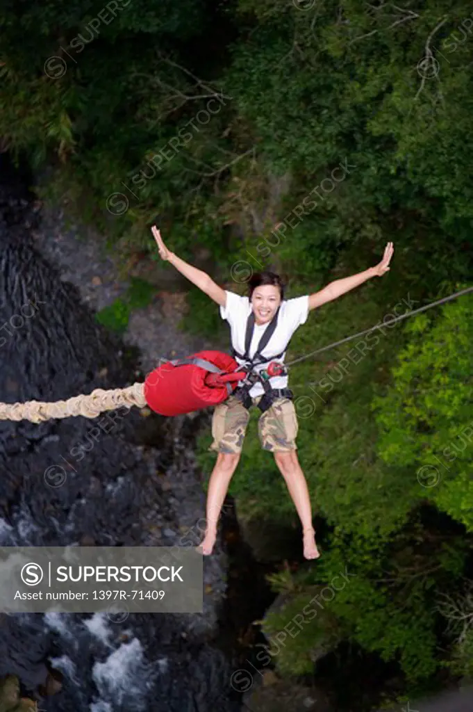 Woman bungee jumping above a stream, overhead view
