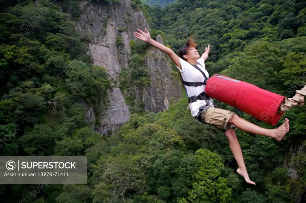 Woman bungee jumping with arms outstretched