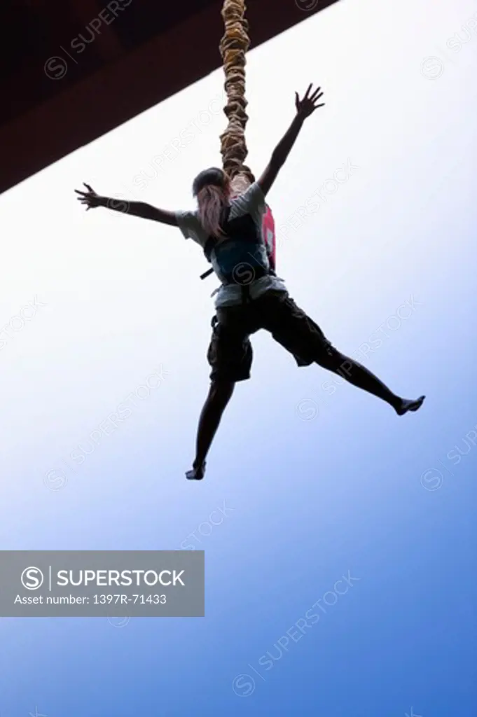 Woman bungee jumping from a bridge, low angle view