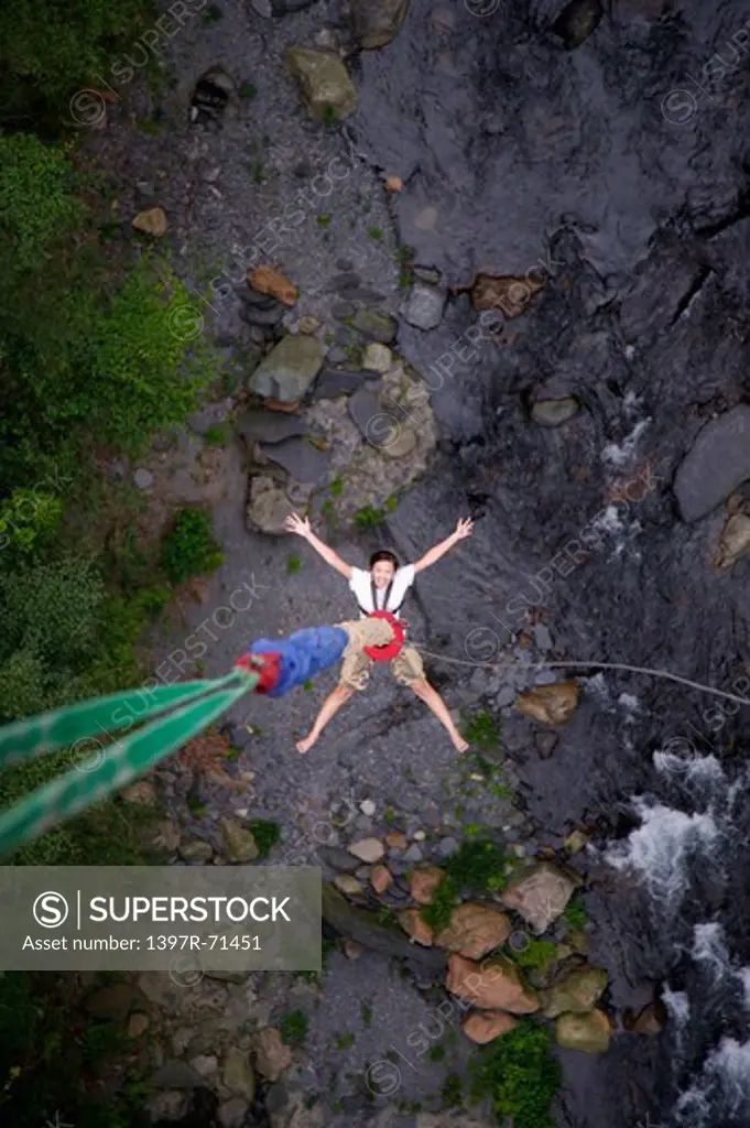 Woman bungee jumping over a stream