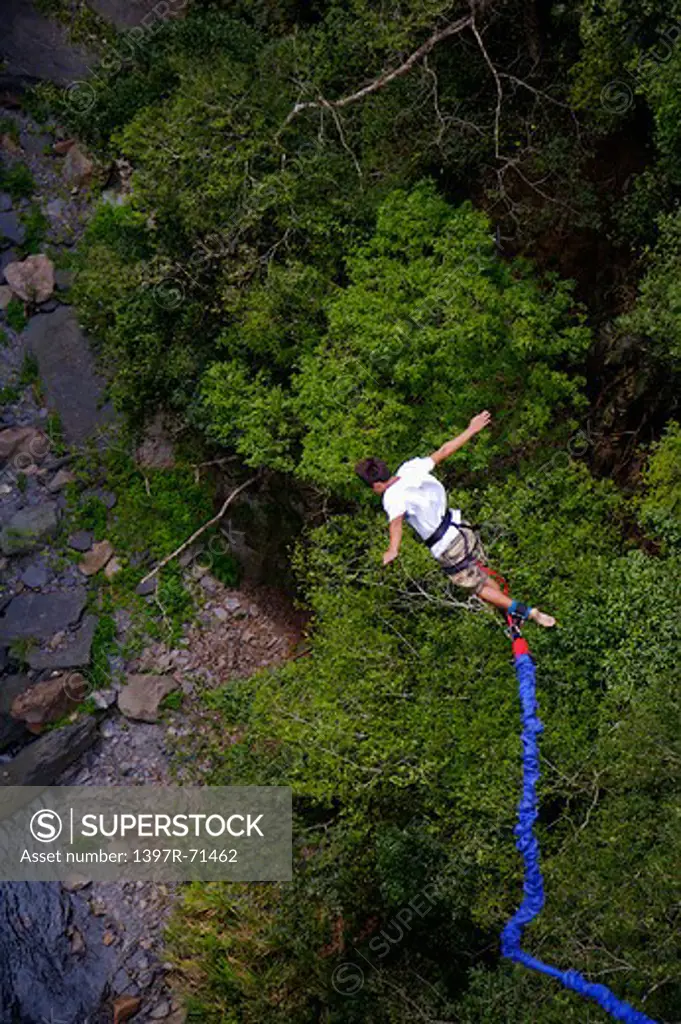 Rear view of male bungee jumper falling with arms outstretched