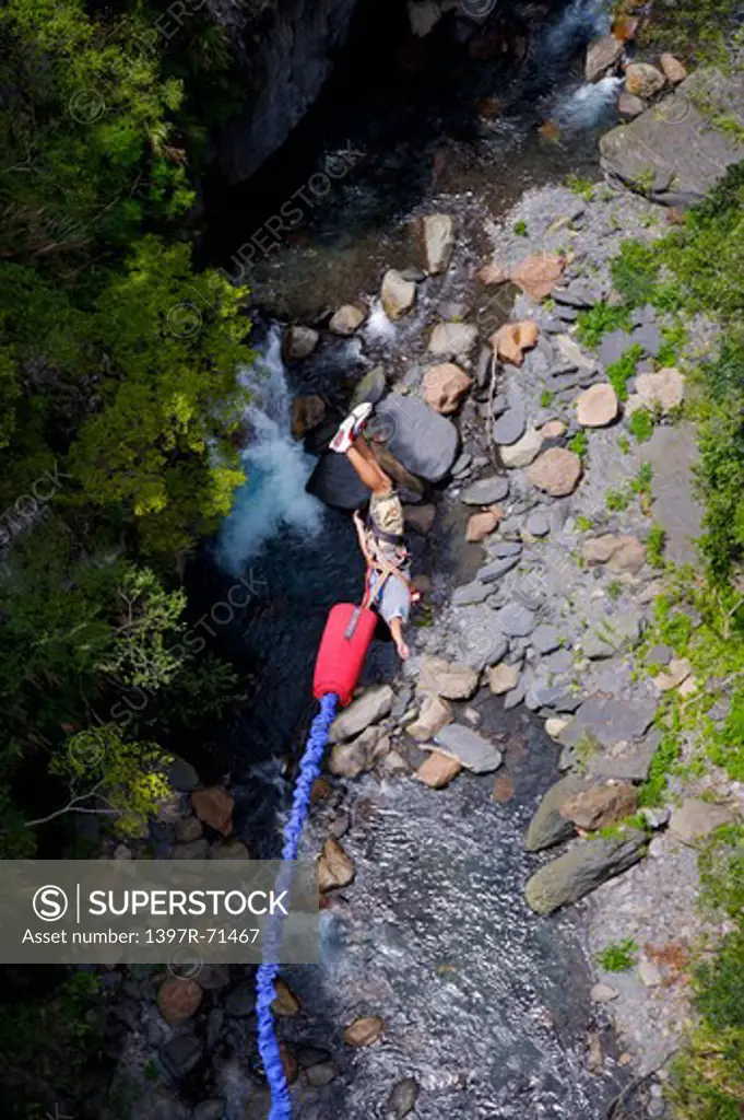 Man bungee jumping toward a stream