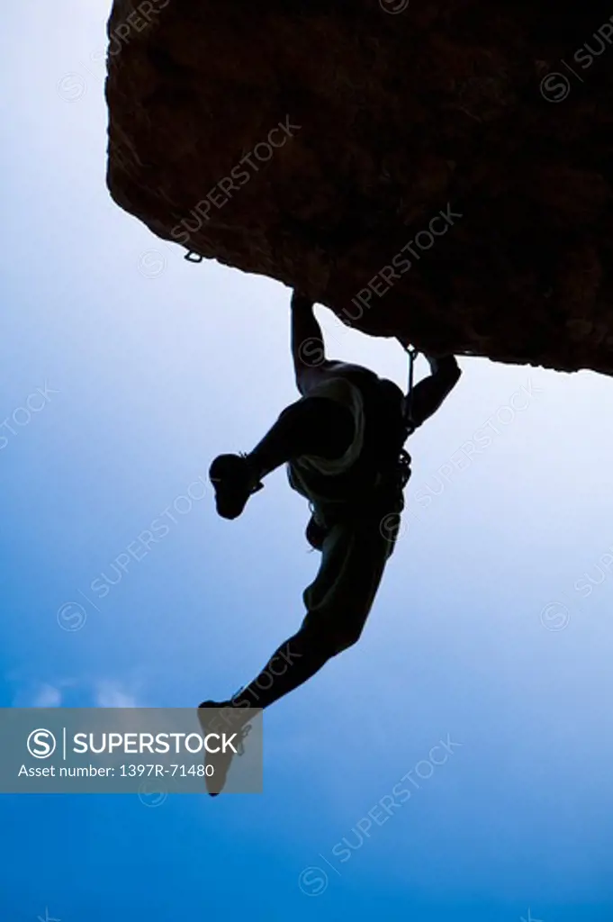 Silhouette of man rock climbing