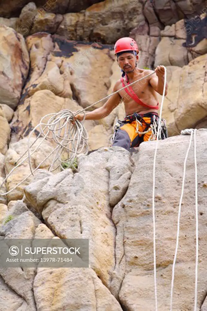 Male rock climber preparing to rappel rock-face