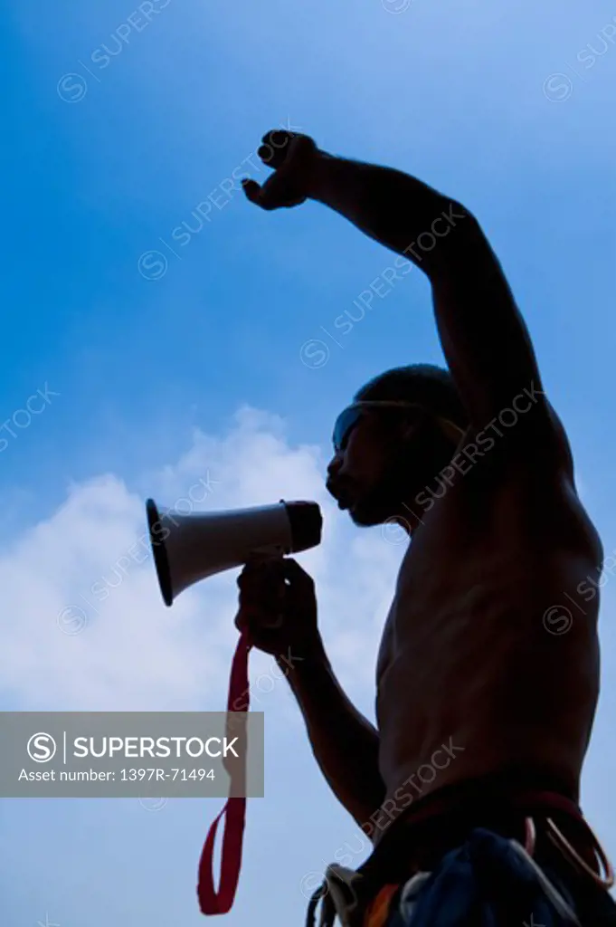 Male rock climber shouting through megaphone