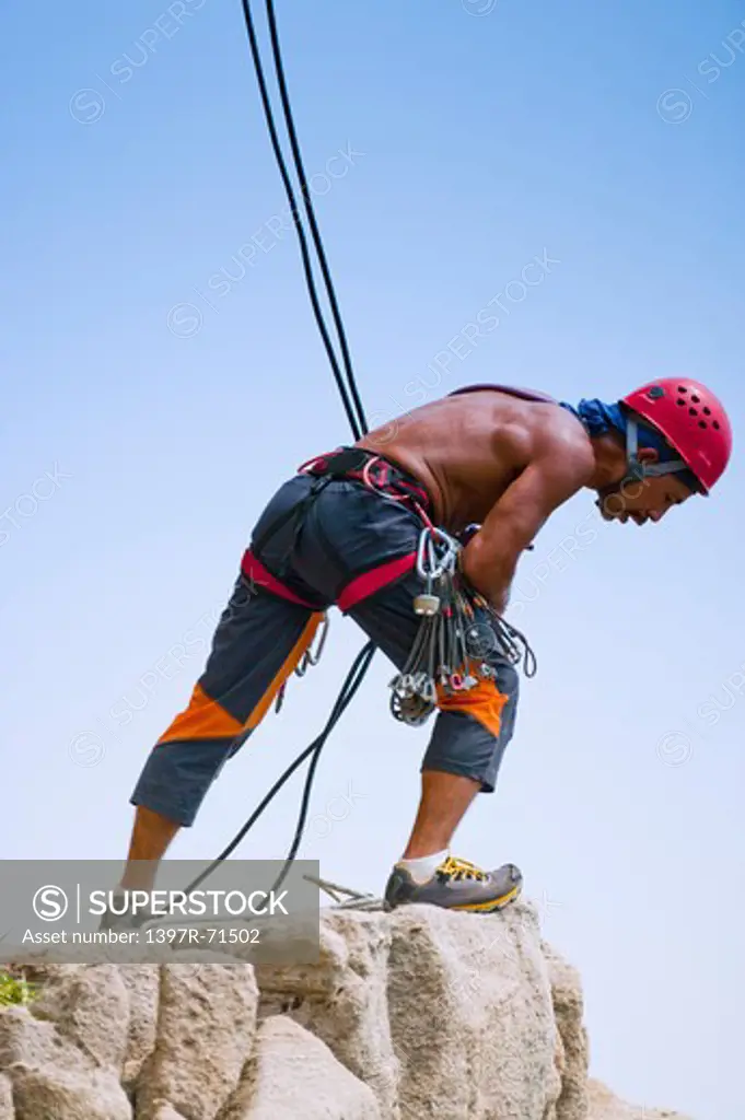 Male rock climber looking down from mountain peak