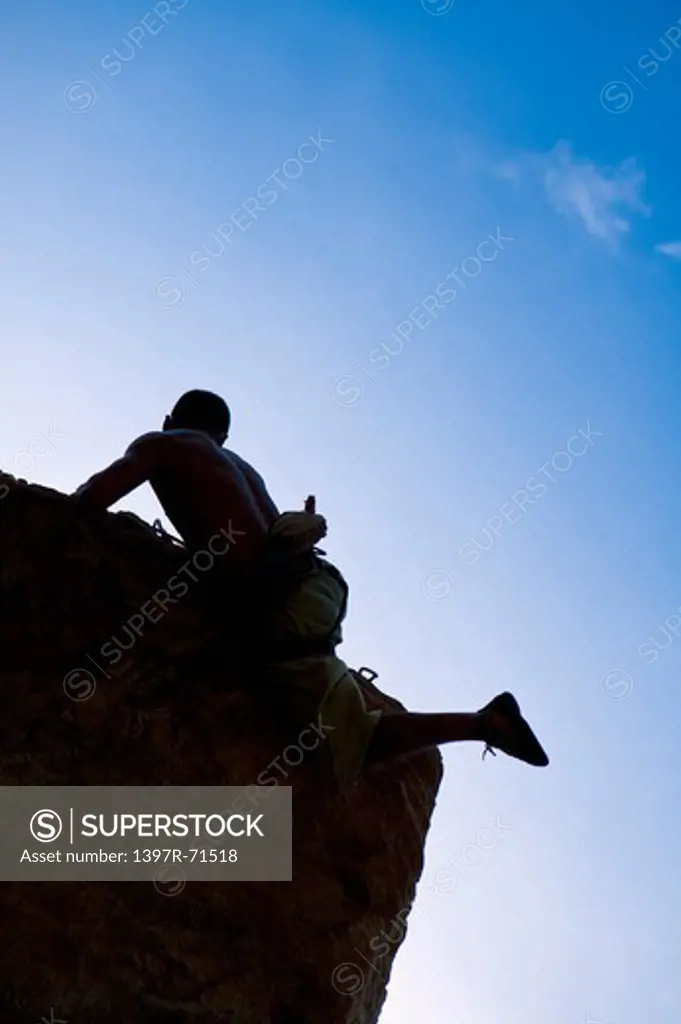 Silhouette of man rock climbing in mountains