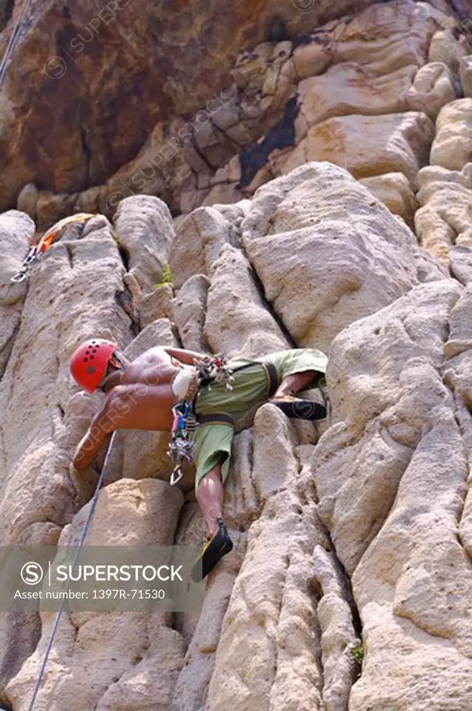 Man rock climbing on cliffs, low angle view