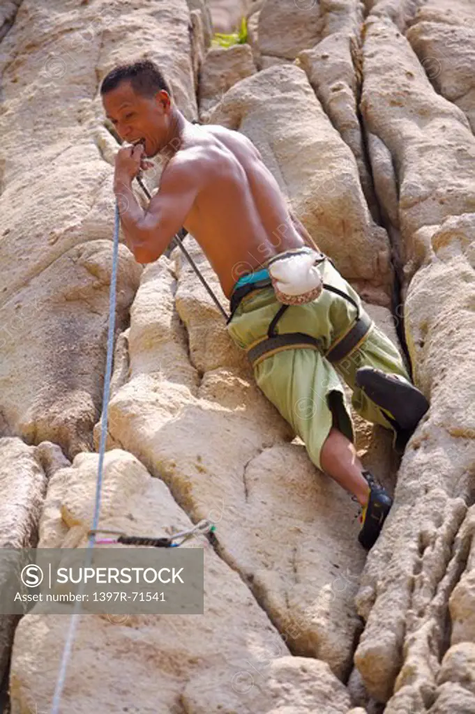 Man rock climbing on cliffs, low angle view
