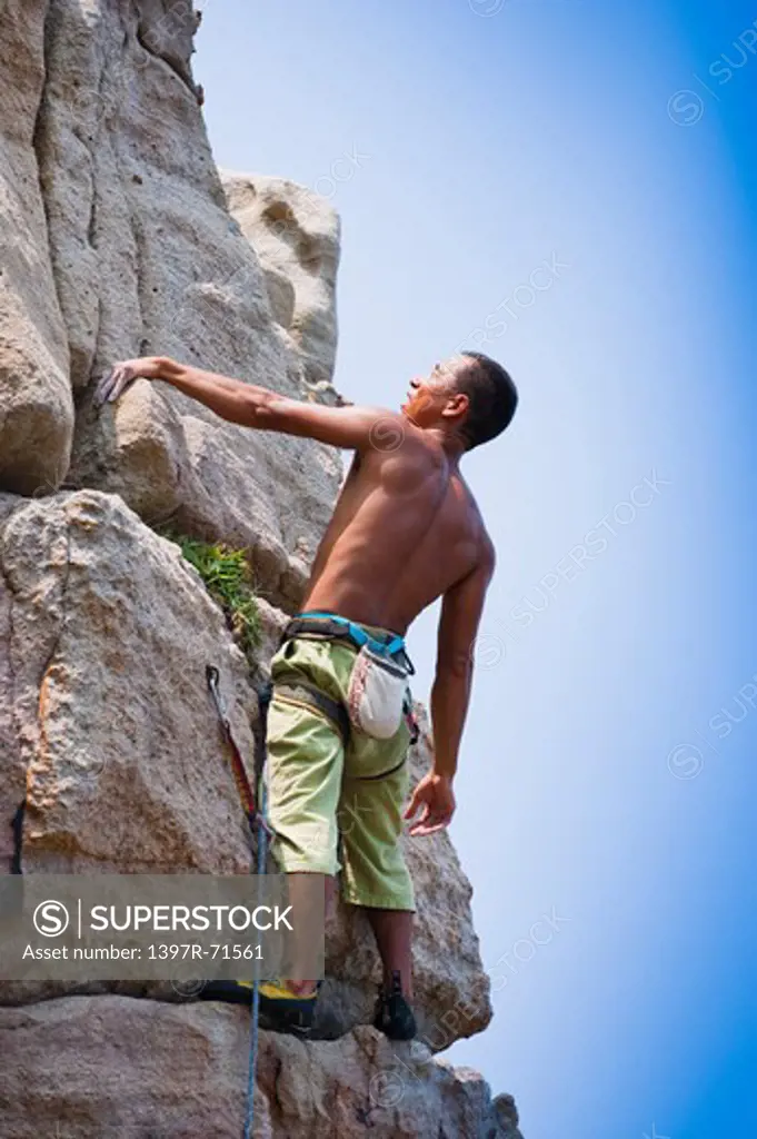 Male rock climber standing on rock and looking up