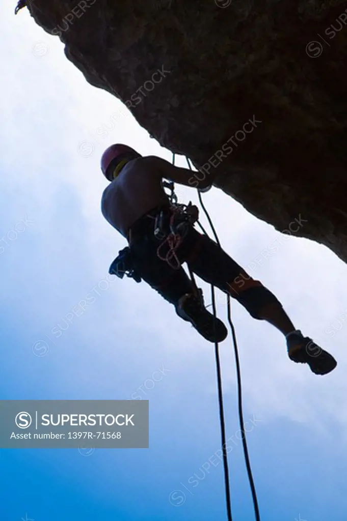 Silhouette of man rock climbing in mountains