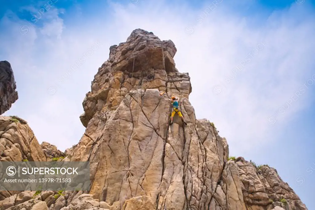 Woman rock climbing on cliffs, low angle view