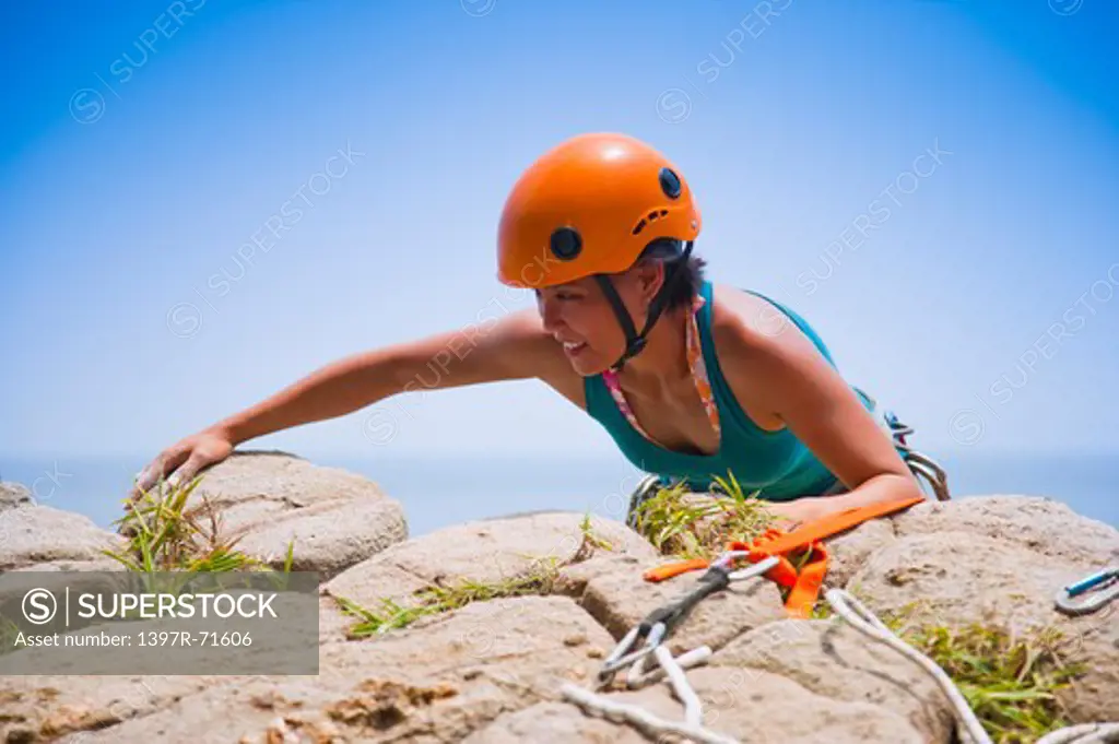 Female rock climber arriving at the top of rock, smiling