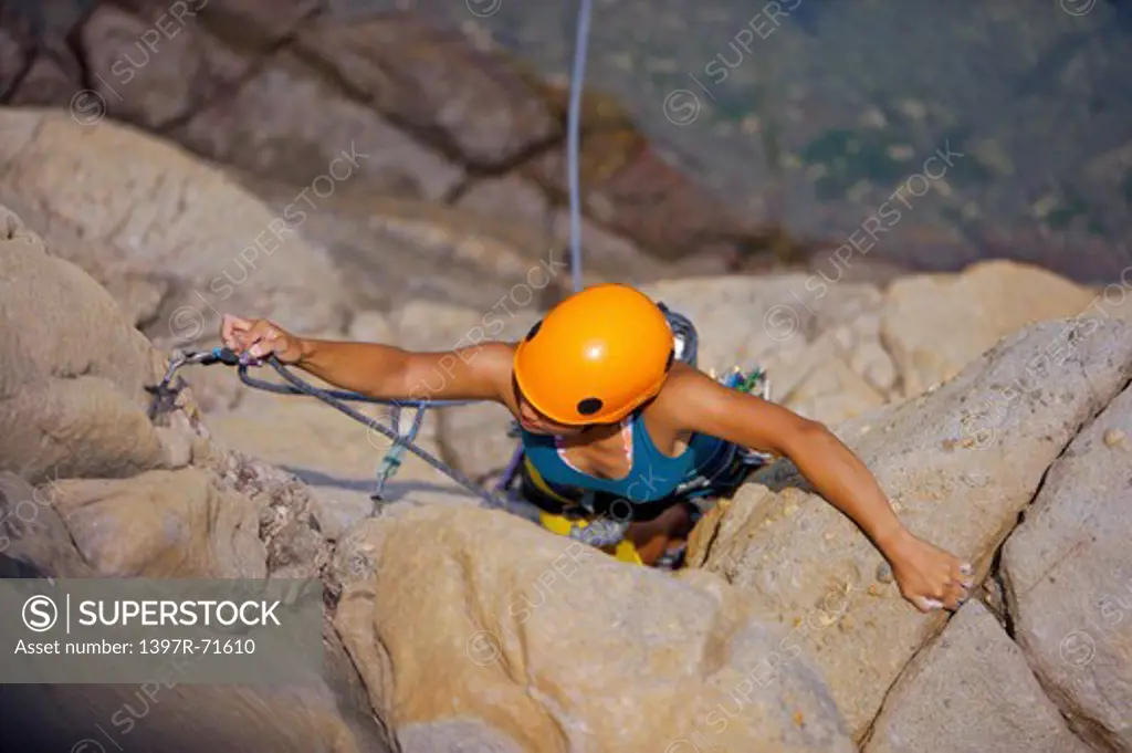 Woman rock climbing on cliffs, high angle view
