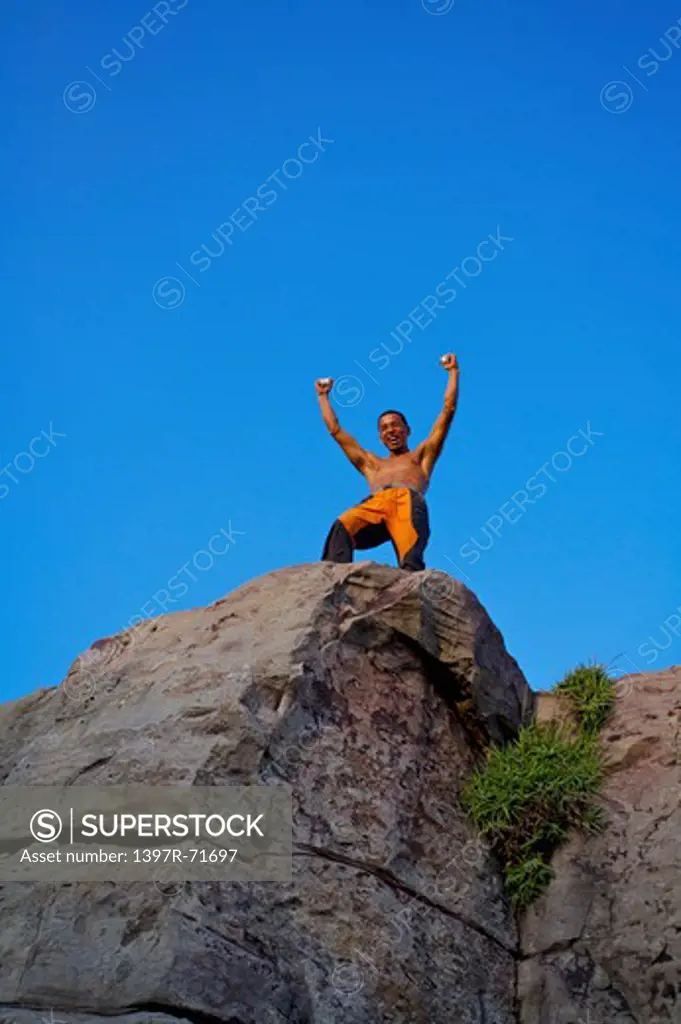 Mature man standing on the cliff with arms outstretched, Rock Climbing, Extreme Sports