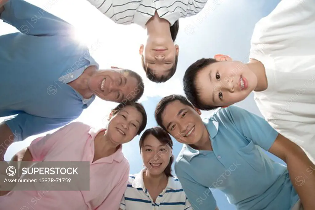 Multi-generational family standing in a huddle, smiling, low angle view