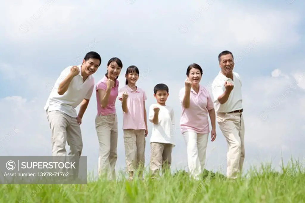 Multi-generational family standing in a row on lawn making fists