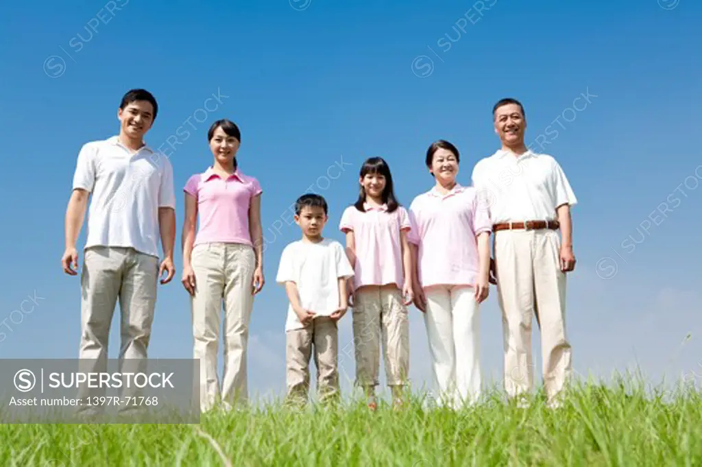 Multi-generational family standing in a row on lawn