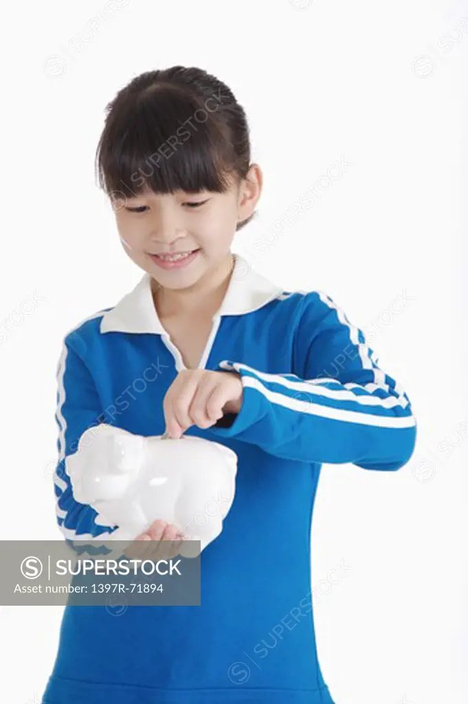 Girl holding piggy bank and looking down with smile