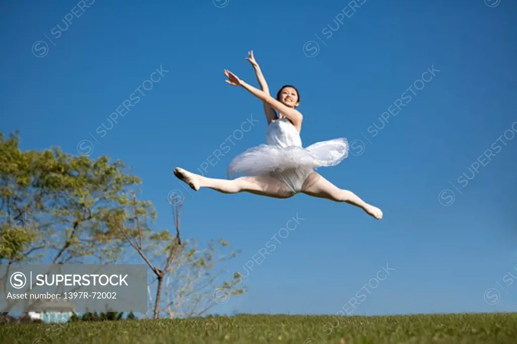 Ballet dancer dancing in mid-air with smile