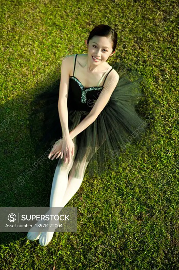 Ballet dancer sitting on the lawn and smiling at the camera