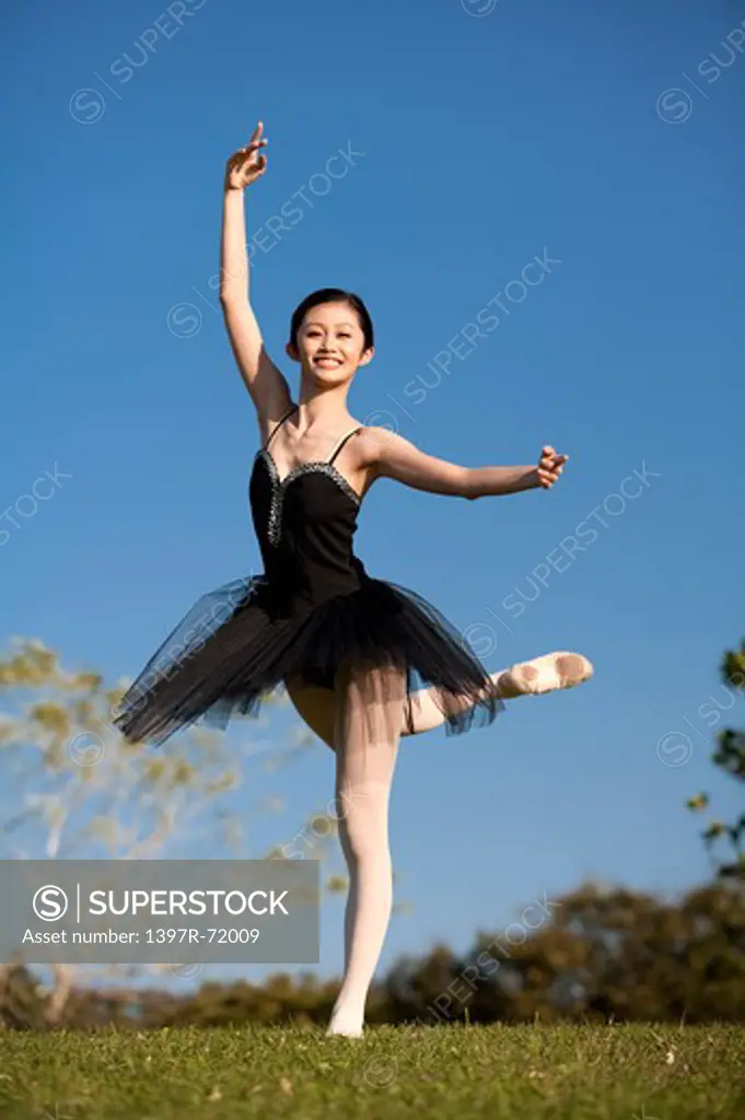 Ballet dancer dancing on the lawn and smiling at the camera