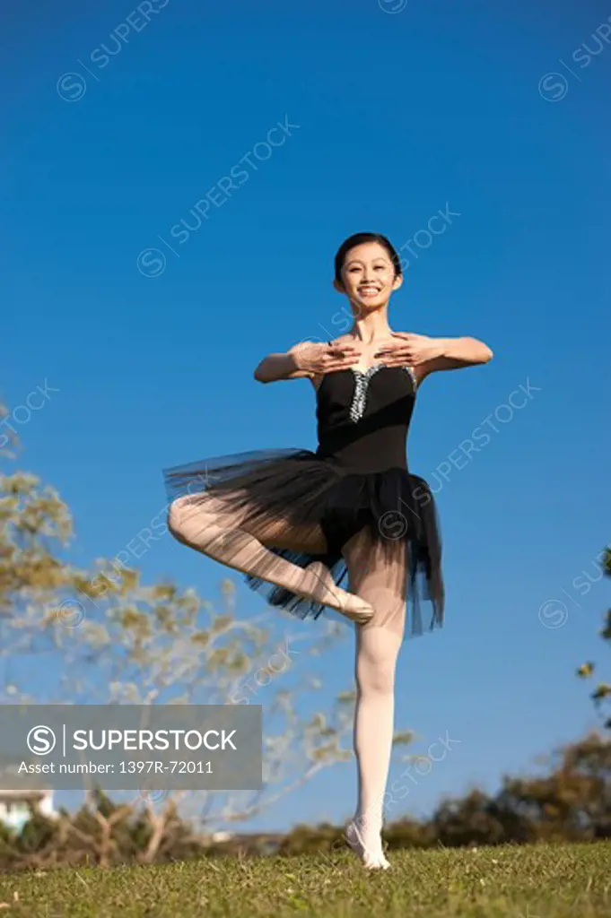 Ballet dancer dancing on the lawn and smiling at the camera