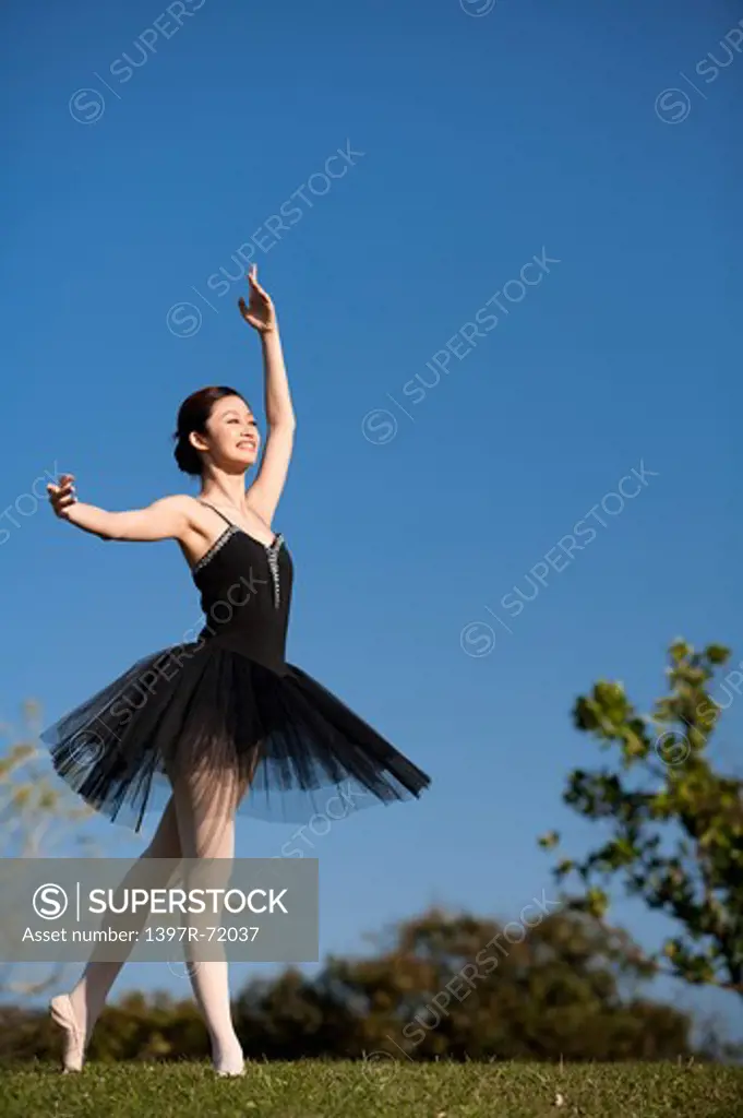 Ballet dancer dancing on the lawn and looking away with smile
