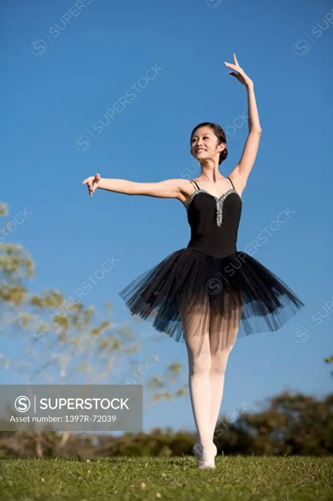 Ballet dancer dancing on the lawn and looking away with smile