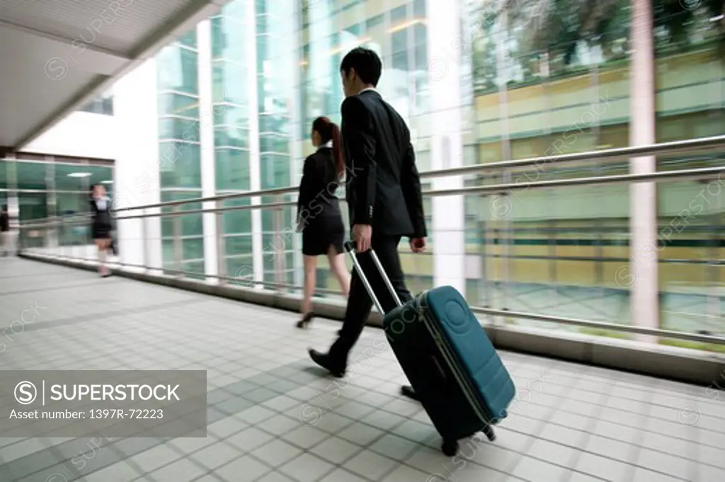 Businessman walking with rolling suitcase