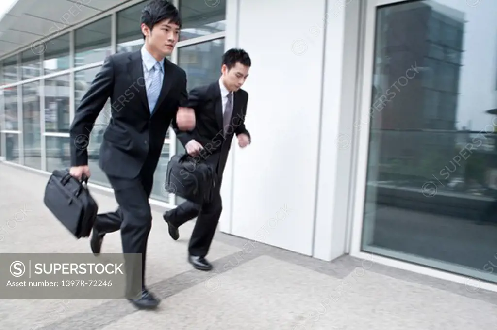 Businessmen running in office building