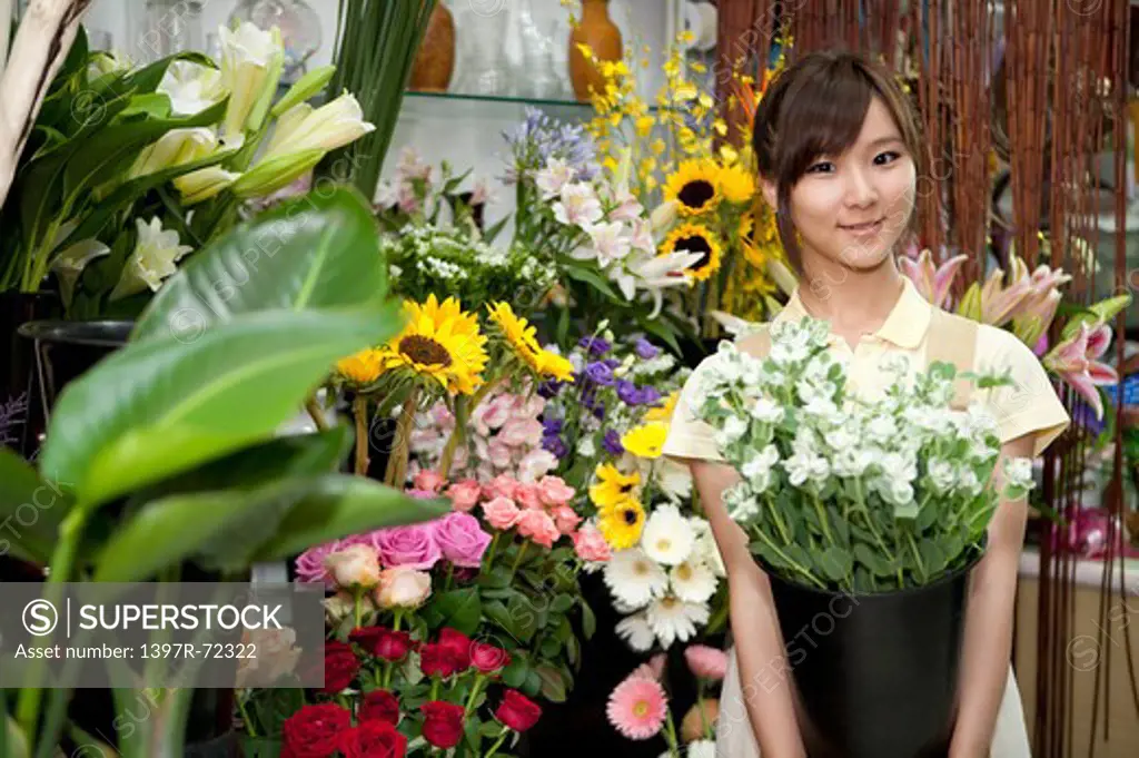 Female florist holding a pot of flowers in the flower shop