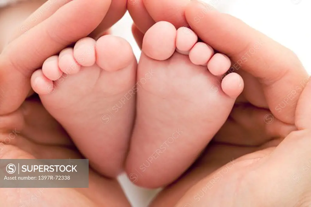 Mother's hands cradling baby's feet