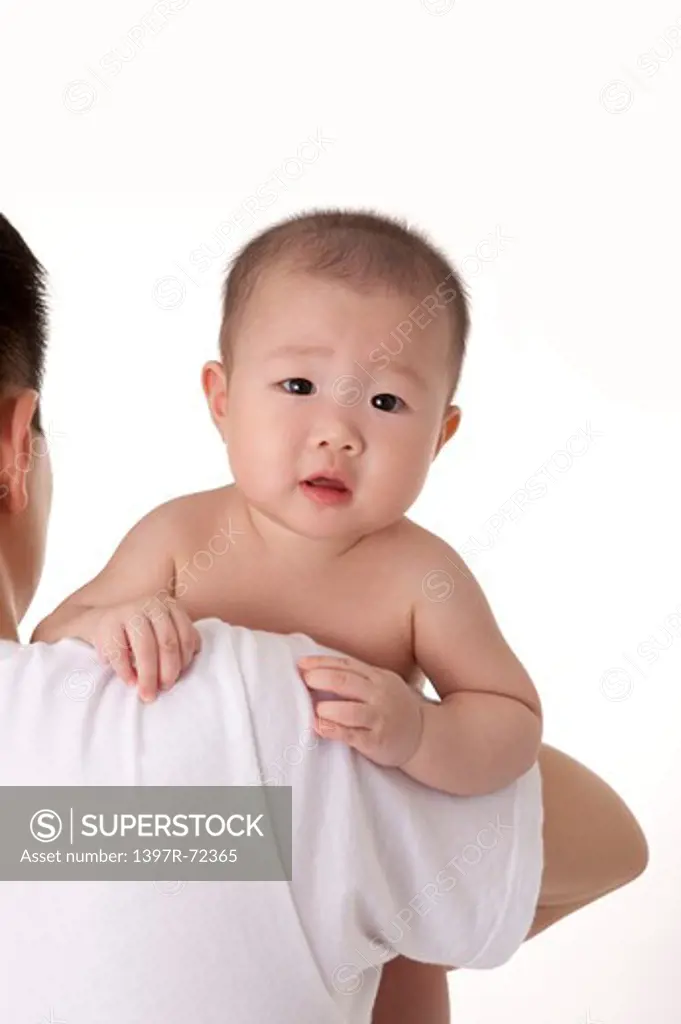 Baby girl looking at the camera from behind father's shoulder