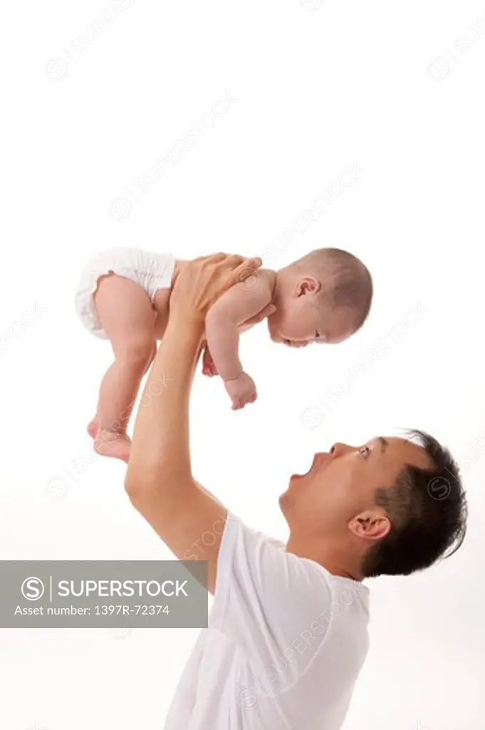 Father lifting baby girl over head,