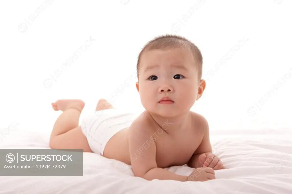 Baby girl lying on front on bed