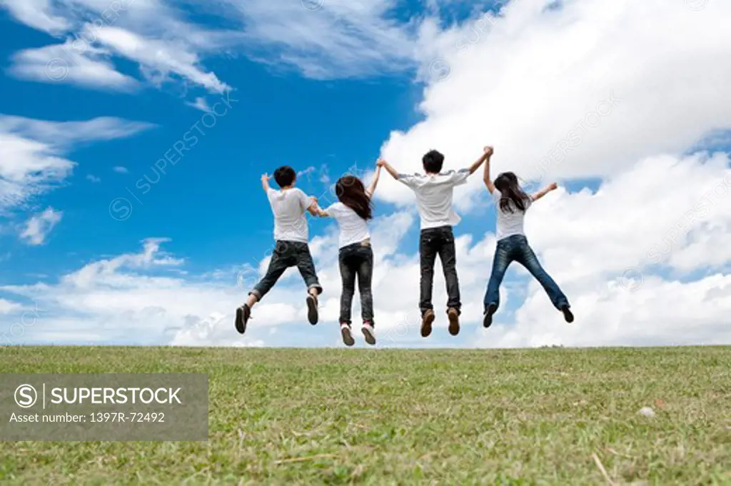 Young adults jumping in mid-air and holding hands together