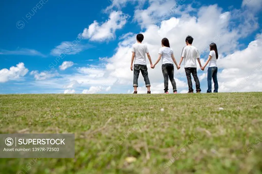 Young adults standing on the lawn and holding hands together