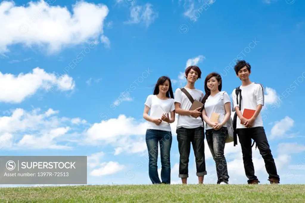 Young adults standing on the lawn and smiling at the camera
