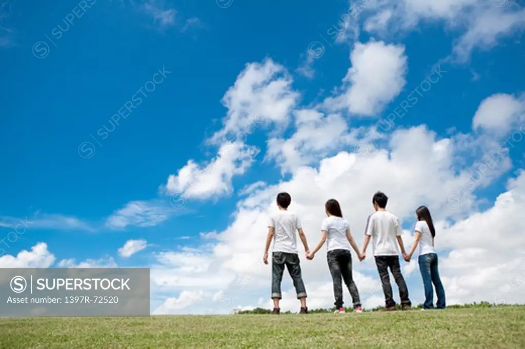 Young adults standing on the lawn and holding hands together