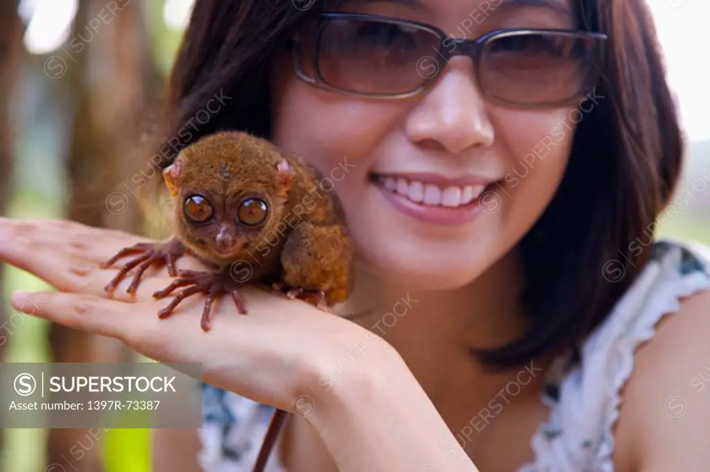 Bohol Island, Cebu, Philippines, Asia, Close-up of woman holding a philippine tarsier with smile