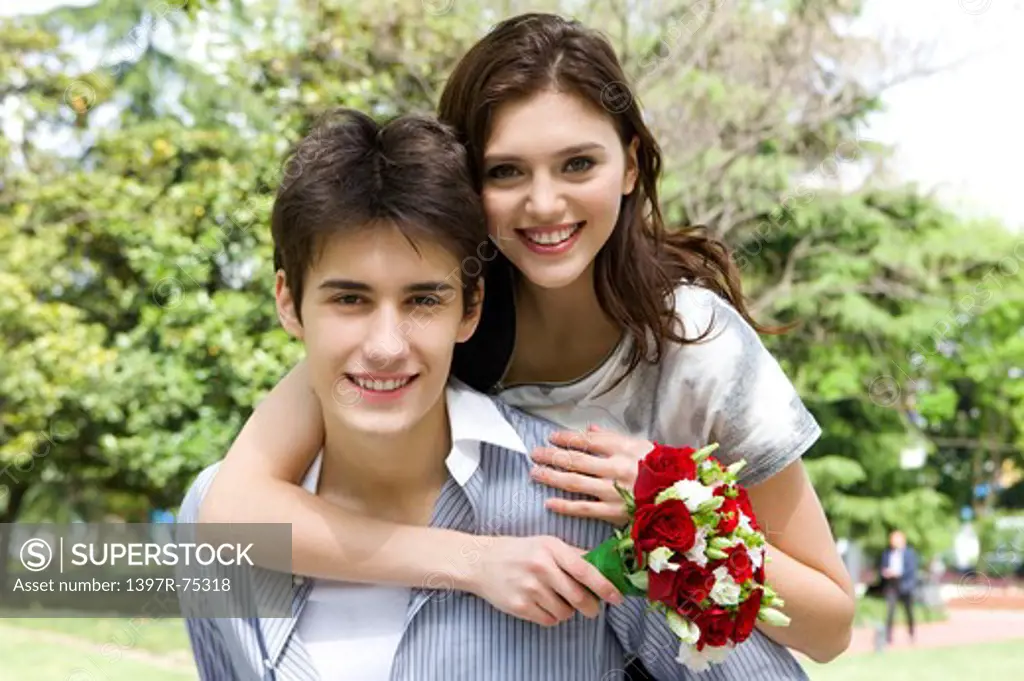 Man piggybacking woman with flowers in hand