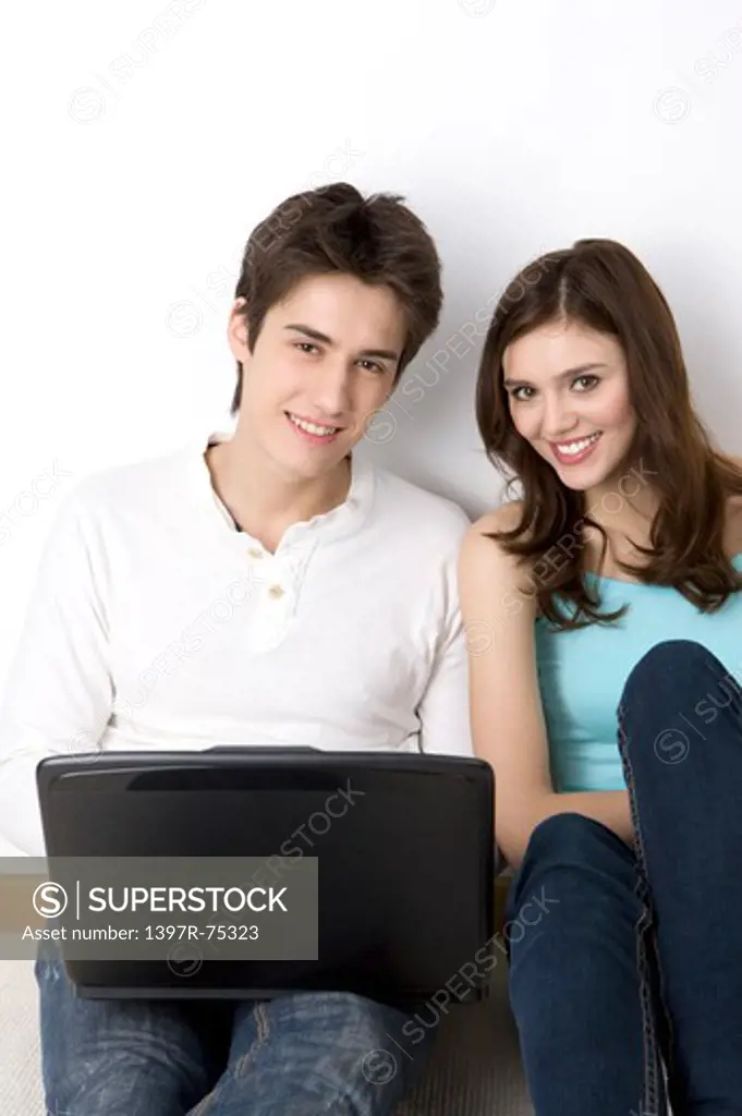 Young couple sitting together with laptop on man's leg