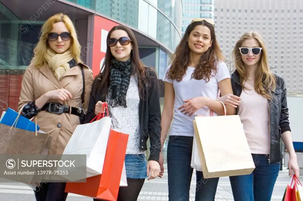 Four young women walking together with shopping bags and smiling, Shopping