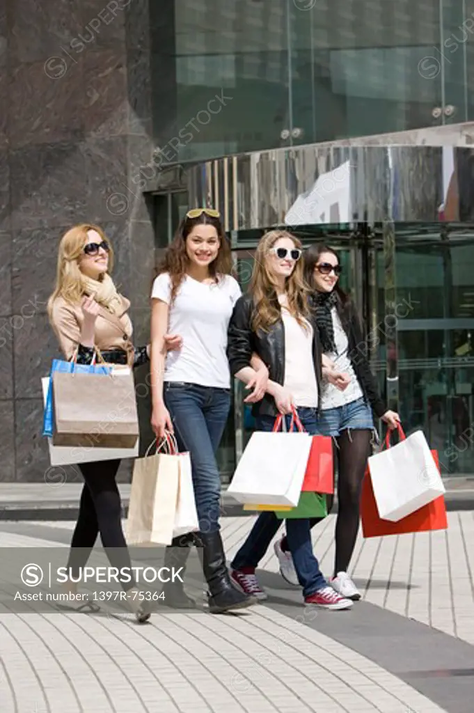 Four young women walking on the street with shopping bags together, Shopping